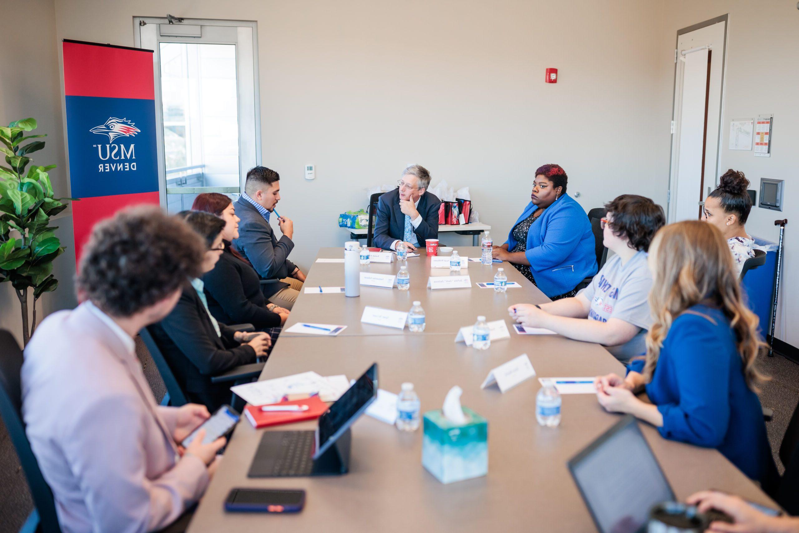 A group meets at a table in one of the CAVEA breakout rooms.