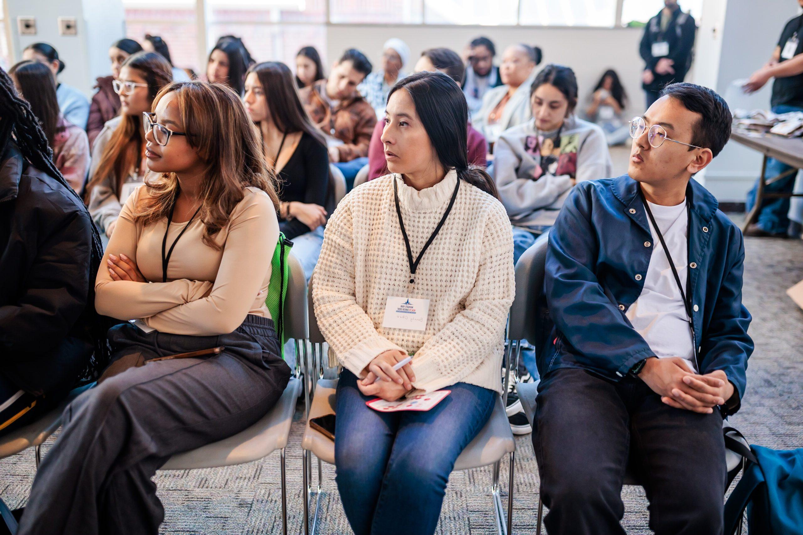 three students sitting in chairs looking right